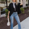 Full body front view of model wearing the Better Than Basic Top that has black knit fabric, a round neckline, and short sleeves with cuffed hems. Top worn with scarf and tucked into jeans.