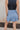 Back view of model wearing the Step It Up Skort in Denim which features dusty blue fabric, shorts lining, a v overlap waistline, slits on each side, and a mini-length hem.