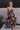 Full body view of model wearing the Beautiful Mess Floral Dress which features black, orange, fuchsia, teal, aqua, green and white fabric, floral print, midi dress, two-tiered body, square neckline, adjustable straps and monochromatic back zipper with hoo