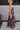 Full body side view of model wearing the Beautiful Mess Floral Dress which features black, orange, fuchsia, teal, aqua, green and white fabric, floral print, midi dress, two-tiered body, square neckline, adjustable straps and monochromatic back zipper wit
