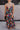 Front view of model wearing the Beautiful Mess Floral Dress which features black, orange, fuchsia, teal, aqua, green and white fabric, floral print, midi dress, two-tiered body, square neckline, adjustable straps and monochromatic back zipper with hook cl