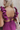 Close up back view of model wearing the Moment in Time Jumpsuit which features plum lightweight fabric, plum lining, wide leg pants, criss cross detail at waist, plunge neckline, ruffle straps, corset ties in the back, open back and monochromatic back zip