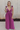 Full body view of model wearing the Moment in Time Jumpsuit which features plum lightweight fabric, plum lining, wide leg pants, criss cross detail at waist, plunge neckline, ruffle straps, corset ties in the back, open back and monochromatic back zipper 