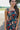 Upper front view of model wearing the Daydreamer Midi Dress in Hunter Green that has hunter green fabric with peach, light pink, purple, blue and olive geometric pattern, midi, smocked upper, square neck, and elastic straps.
