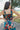 Upper back view of model wearing the Daydreamer Midi Dress in Hunter Green that has hunter green fabric with peach, light pink, purple, blue and olive geometric pattern, midi, smocked upper, square neck, and elastic straps.