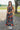 Front view of model wearing the Daydreamer Midi Dress in Hunter Green that has hunter green fabric with peach, light pink, purple, blue and olive geometric pattern, midi, smocked upper, square neck, and elastic straps.