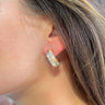 Side view of model wearing the Checkmate Earring in Natural which features grey, taupe and tan square beads, checkered design and mini open hoops with gold details.