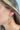 Side view of model wearing the Cheap Thrills Earrings which features scooped, closed hoops with gold lines design.