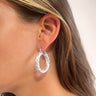 Side view of model wearing the Spin You Around Earrings which features closed medium size silver braided hoops.