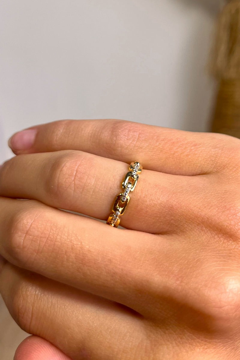 Close up view of model wearing the Unbreakable Chain Ring which features single gold band with chain and clear stones design.