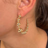 Side view of model wearing the Full Of Life Hoops in Gold which features large, open gold hoops with small and large gold beads.