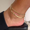Side view of model wearing the Double The Trouble Anklet which features two gold layers, one layer with gold flat design and the other layer is a gold roping design.