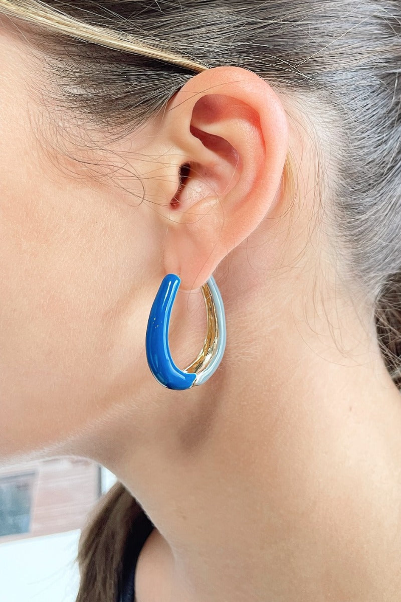 Side view of model wearing the Around The Block Earrings in Blue which features medium, closed hoops with grey and blue color-block design.