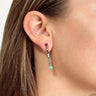 Side view of model wearing the Reputation Earrings in Multi which features gold dangle bar with turquoise, pink, black, white and green stones.