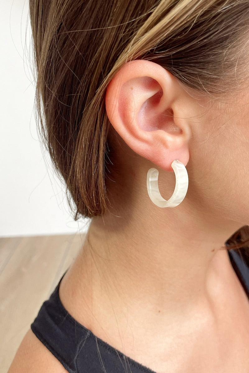 Side view of model wearing the Keep It Simple Earrings in Ivory which features small, open hoops with cream tortoise design.