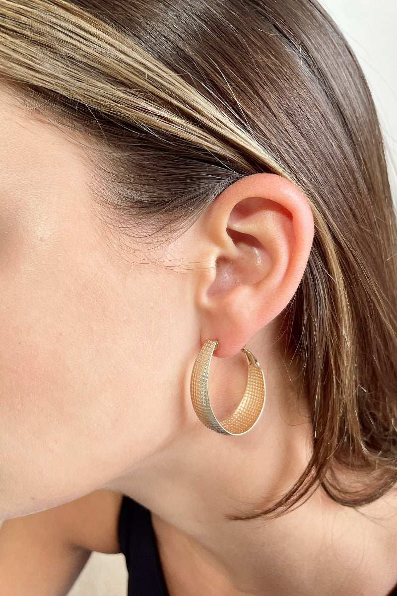 Side view of model wearing the Krista Hoop Earrings which features scooped, closed hoops with monochromatic speckled design.