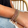 Front view of model wearing the Unforgettable Bracelet Set in Light Pink which features five stack of stretchy bracelets with three light pink small beaded bracelets and two gold small beaded bracelets.