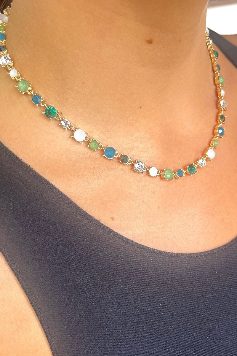 Front view of model wearing the Karma Necklace in Multi Green which features multi green, teal, sage, clear and white color stones set in gold with an adjustable gold chain link.