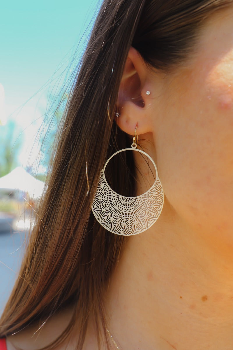 Front view of model wearing theTwo Sides Earring in Ivory which features ivory open circle with leaf design and gold hardware.