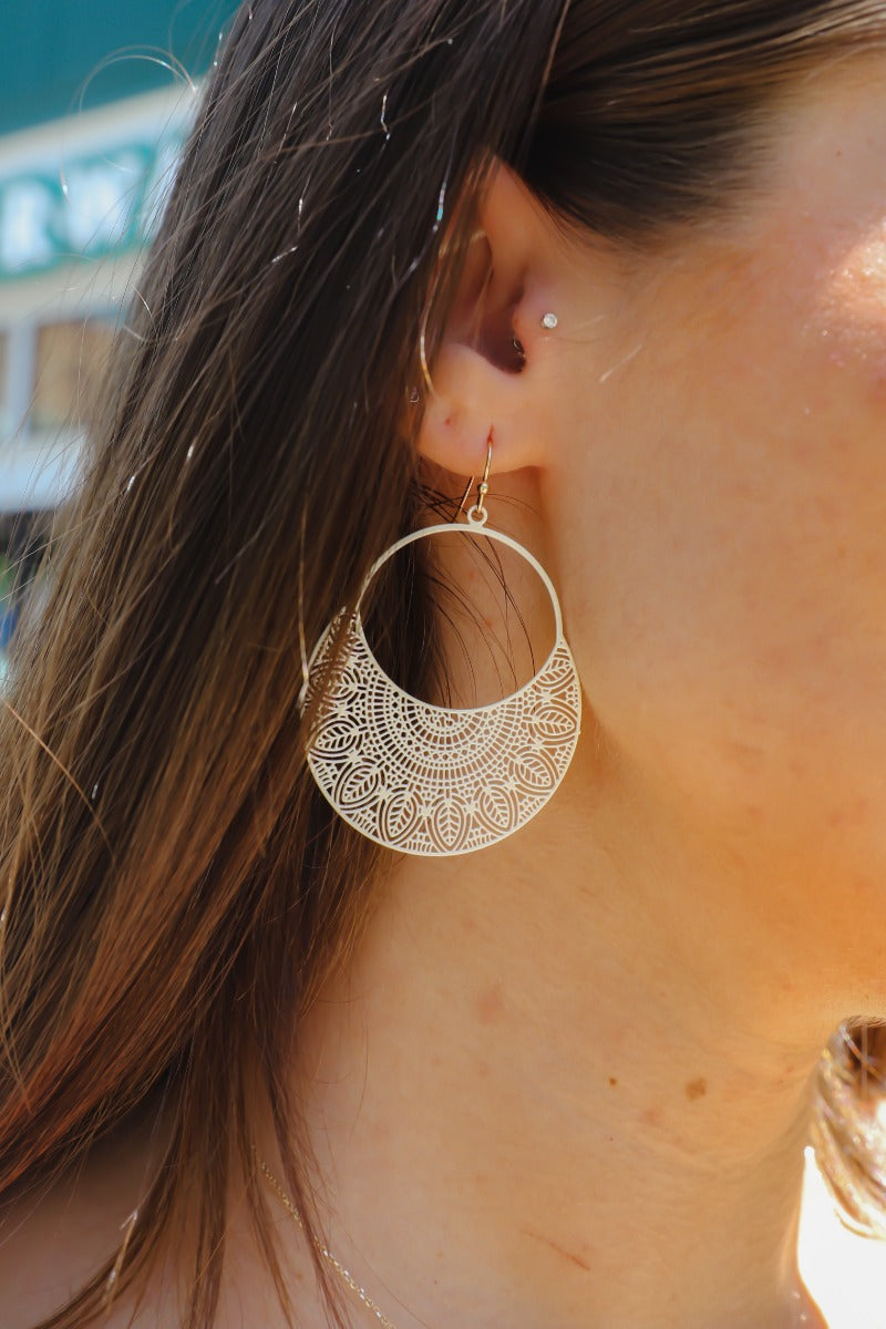 Front view of model wearing theTwo Sides Earring in Ivory which features ivory open circle with leaf design and gold hardware.