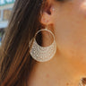 Front view of model wearing theTwo Sides Earring in Ivory which features ivory open circle with leaf design and gold hardware.