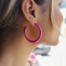 Side view of model wearing the Shine Bright Earrings in Pink which features open medium size hot pink hoops.