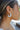 Side view of model wearing the It's Simple Earring in White which features white, medium, shaped hoops with white lines attaching each side.
