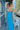 Back view of model wearing the Coastal Paradise Dress that has cobalt blue ribbed fabric, midi length, a round neckline, an elastic waistband, and spaghetti straps