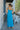 Full body back view of model wearing the Coastal Paradise Dress that has cobalt blue ribbed fabric, midi length, a round neckline, an elastic waistband, and spaghetti straps