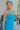 Close side view of model wearing the Coastal Paradise Dress that has cobalt blue ribbed fabric, midi length, a round neckline, an elastic waistband, and spaghetti straps