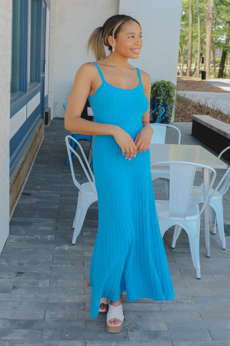 Full body front view of model wearing the Coastal Paradise Dress that has cobalt blue ribbed fabric, midi length, a round neckline, an elastic waistband, and spaghetti straps