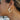 Side view of model wearing the Wanderlust Multi Hoop Earring which features white, open, small size hoops with light blue, light green and yellow geometric design with gold details.