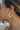 Side view of model wearing the Wanderlust Multi Hoop Earring which features white, open, small size hoops with light blue, light green and yellow geometric design with gold details.