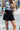 Front view of model wearing the Going Coastal Shorts in Black that have black fabric, pockets on each side, an elastic waistband and a folded hem.