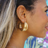 Side view of model wearing the Level Up Gold Hoop which features open-shaped gold hoops with braided knot design.