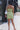 Full body back view of model wearing the New Adventure Dress that has light green fabric, a mini length hem, cutouts on each side, a sweetheart neck, an open back with smocking, a back zipper closure, and adjustable straps.