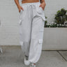 Front view of model wearing the Pushing Forward Joggers which features light heather grey fabric, elastic waistband with drawstring ties, two front pockets, cargo pockets on each side and jogger pant legs with elastic ankles.