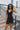 Front view of model wearing the Comfort Zone Lightweight Romper which features stretchy black fabric, a scooped neckline, a racerback, a built in bra, and fitted shorts.