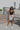 Full body view of model wearing the Comfort Zone Lightweight Romper which features stretchy black fabric, a scooped neckline, a racerback, a built in bra, and fitted shorts.