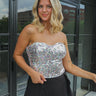 Front view of model wearing the Style With Sparkle Top which features multi-colored sequin fabric, white lining, a cropped waist, a strapless sweetheart neckline, and a back zipper and hook closure.