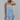 Front view of model wearing the Now Or Never Dress which features light blue textured fabric, a ruffle two-tiered mini-length body, light blue lining, a square neckline, and thick straps.