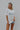 Front view of model wearing the ACDC: World Tour 1980 Graphic Tee which features white and grey fabric with distressed details, a round neckline, and short sleeves. Graphic says "World Tour ACDC 1980" with a globe graphic.