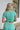 Back view of model wearing the Mint To Be Top that has mint green ribbed fabric, a cropped waist, a round neckline, and short sleeves