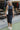 Front view of model wearing the Bristol Ruched Midi Dress in Black that has black knit fabric, midi length, ruched side details, a side slit, a round neckline and a sleeveless design