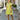 Full body front view of model wearing the Brighter Days Ahead Dress that has lime green fabric, a three-tiered body style,, a smocked elastic waist, tie details, a v neck with ruffles, and short sleeves