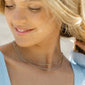 Model is wearing the Aubrey Mixed Metal Necklace that has a silver chain and two gold chains with gold beads.