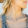 Close up of model wearing the Clear As Day Necklace that has a gold link chain with clear beads.