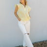 Full body front view of model wearing the Feels Like Sunshine Top that has yellow gauze fabric, a scoop neckline with a v-cutout, and ruffle short sleeves.
