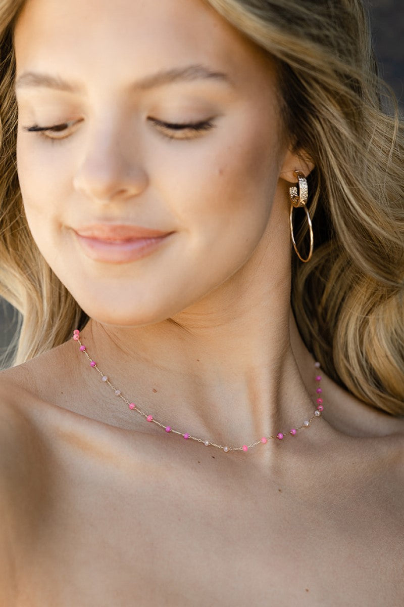 Close up of model wearing the Pretty in Pink Necklace that has a gold link chain with hot pink, bright pink and light pink beads.