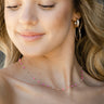 Close up of model wearing the Pretty in Pink Necklace that has a gold link chain with hot pink, bright pink and light pink beads.